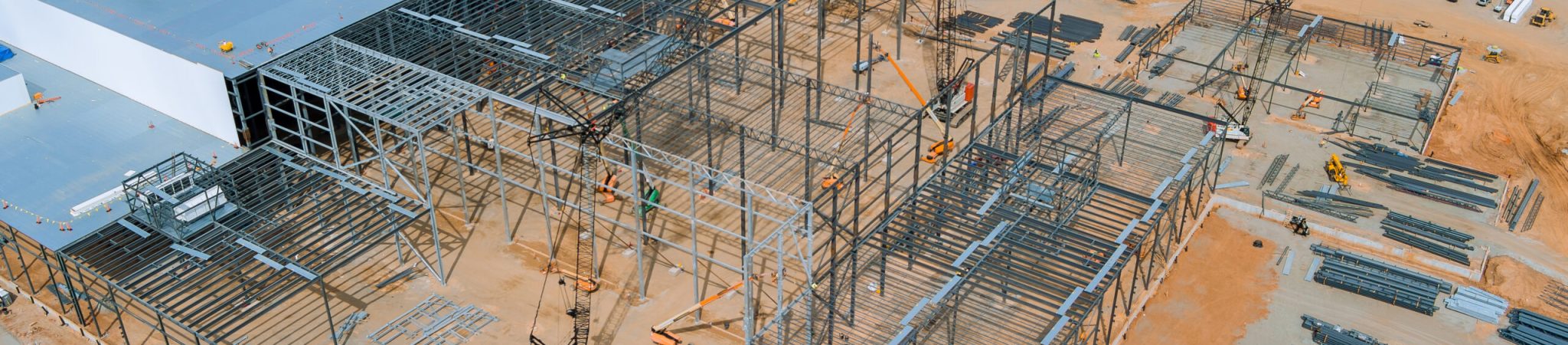 Installing metal frame for steel warehouse construction frame work large cranes in construction site